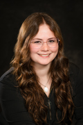 Professional photo of Torri Evans wearing a black shirt and glasses.
