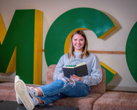 Photo of MCC Student Reading a book with a smile.