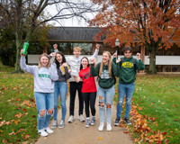 Group of Students Outside on MCC Campus waving their hands in the air.