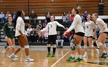 A group of MCC volleyball players gather to celebrate after a point being scored during a match.
