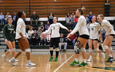 A group of MCC volleyball players gather to celebrate after a point being scored during a match.