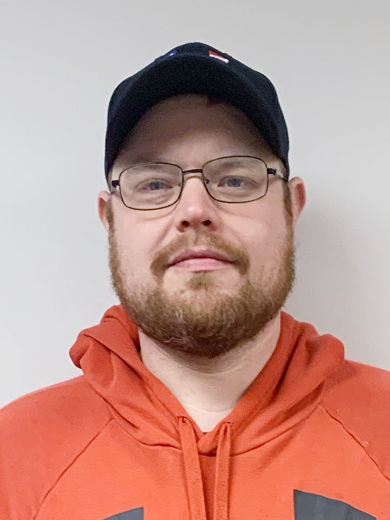 Headshot of Brian Chartrand wearing a orange sweatshirt, black hat and glasses.