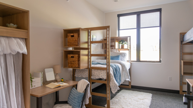 Styled bedroom of Carbonelli Villas showing off a lofter bed and desk. 