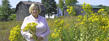 MCCF Scholarship creator, Sue Ann Aargaard standing outside near yellow flowers on the Sidney campus.