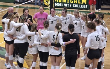 MCC women's volleyball team standing in a circle on the court before the start of their home opener.
