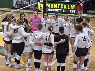MCC women's volleyball team standing in a circle on the court before the start of their home opener.