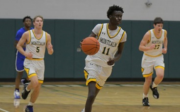Three MCC men's basketball players running down the court during a game. Number 11 is dribbling the ball and is flanked by number 5 and number 23.