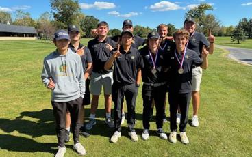 MCC golf team posing with pointer finder up to signal number 1