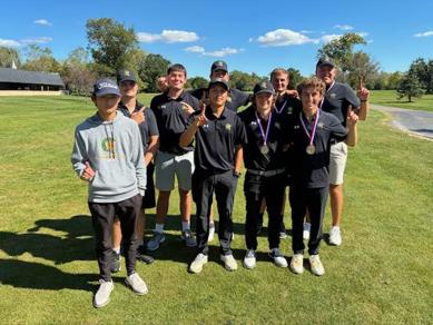 MCC golf team posing with pointer finder up to signal number 1