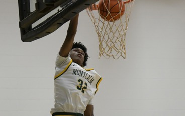 MCC men's basketball player dunking the ball during a game. His uniform number is 32.