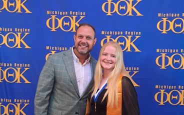 MCC President Bradley Barrick and MCC PTK Officer and student Lariah Tissue standing in front of a PTK backdrop.