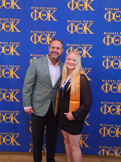 MCC President Bradley Barrick and MCC PTK Officer and student Lariah Tissue standing in front of a PTK backdrop.