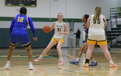 MCC women's basketball player Emma Rehkopf dribbles the ball on the home court during a game with opposing players an teammates surronding her.