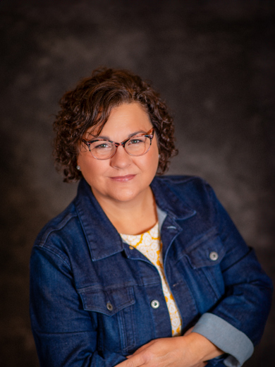 Headshot of instructor Kristen Diehl wearing a jean jacket with her arms crossed and smiling at the camera.