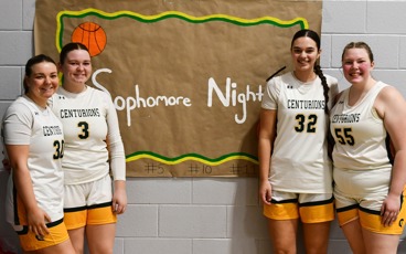 Four MCC women's basketball players standing in front of a sign that reads "Sophomore Night"