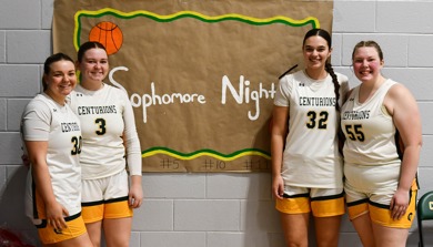 Four MCC women's basketball players standing in front of a sign that reads "Sophomore Night"