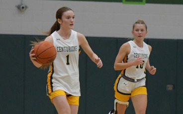 Two MCC women's basketball players running down the court. Number 1 is dribbling the ball while number 10 runs next to her and looks on.
