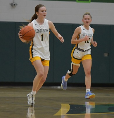 Two MCC women's basketball players running down the court. Number 1 is dribbling the ball while number 10 runs next to her and looks on.