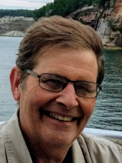 Headshot of Paul Willy with cliffs and trees in the background.