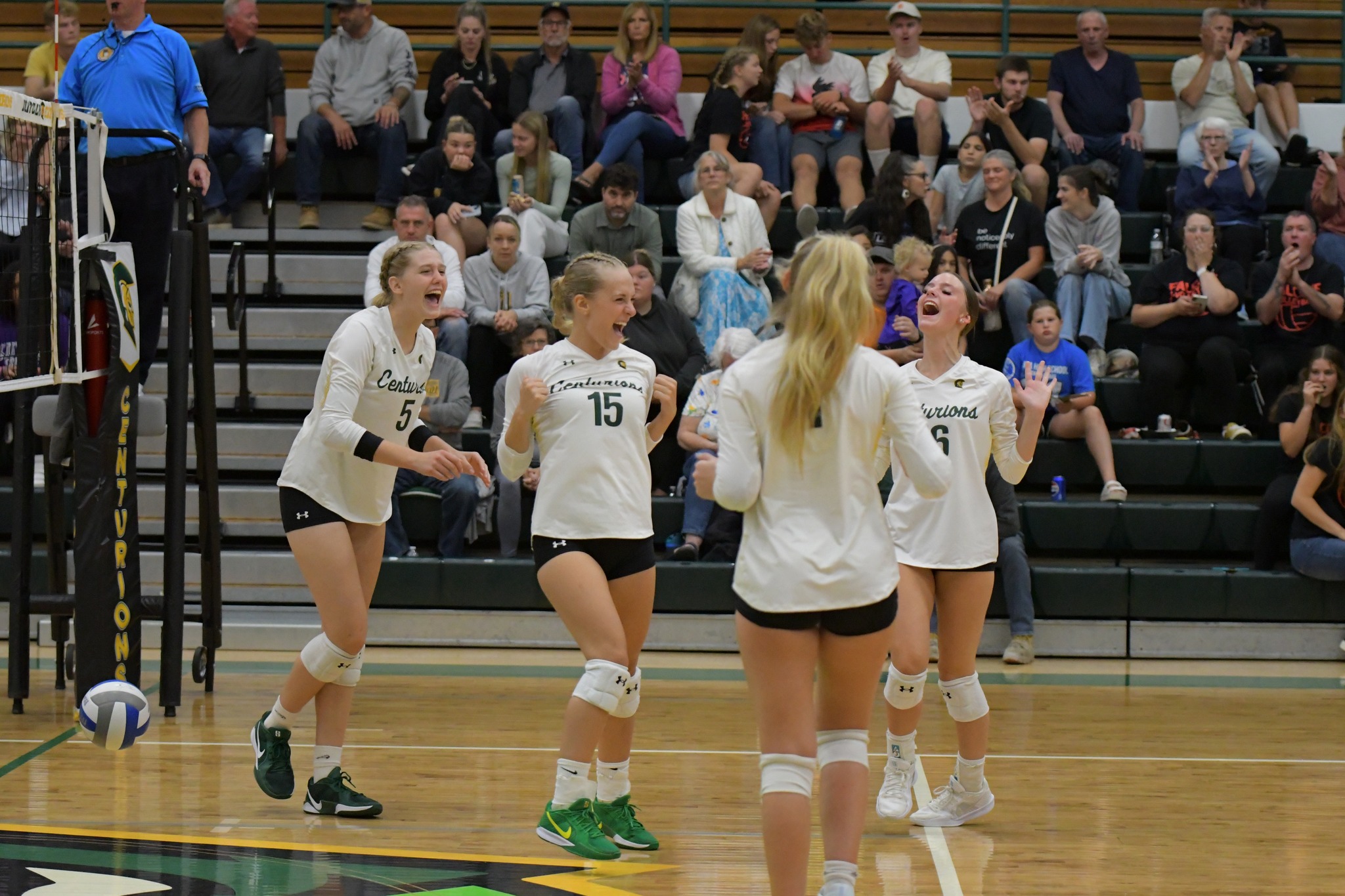 Four MCC women's volleyball players celebrating on the court together.
